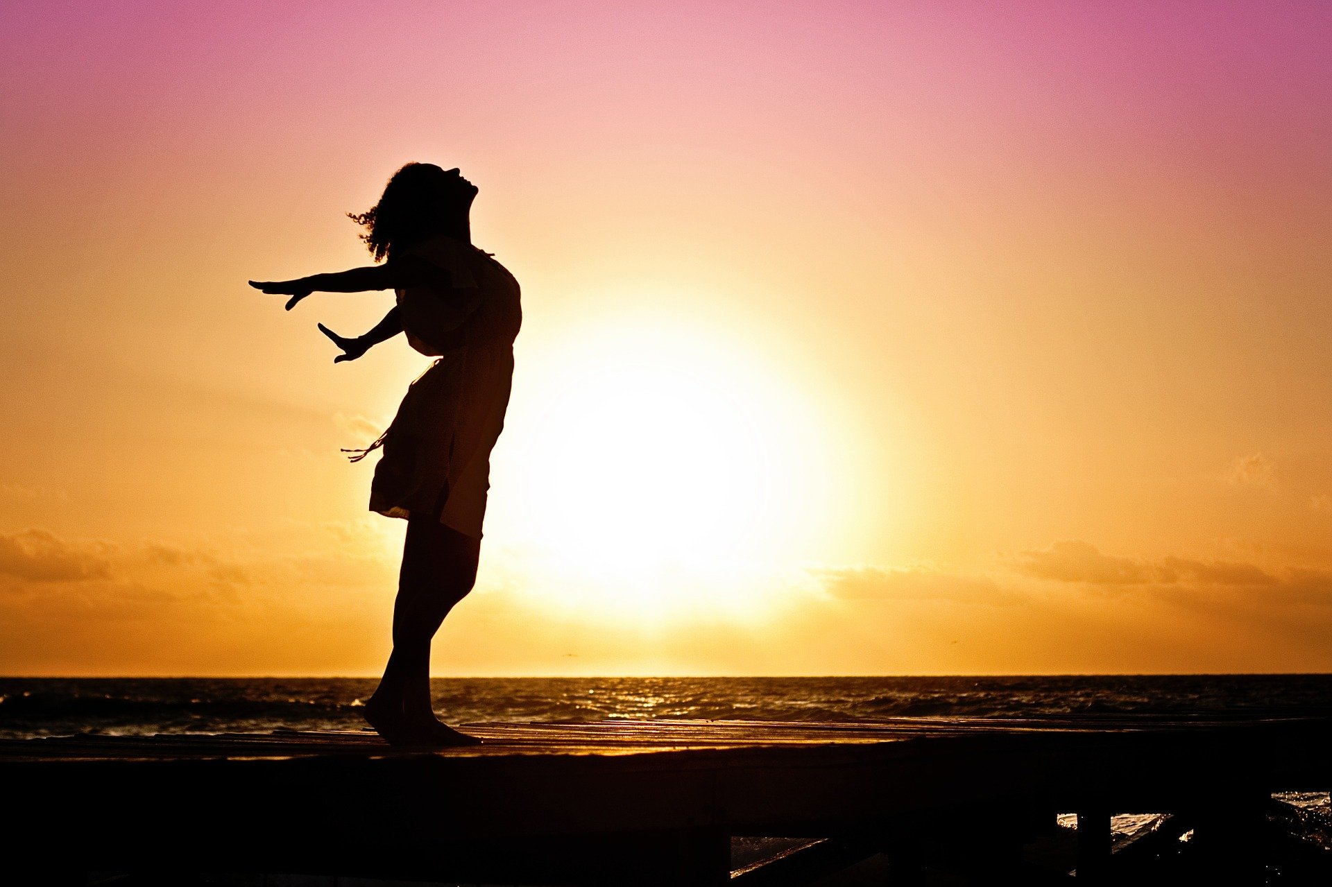 Woman's silhouette in front of a purple and orange sunset